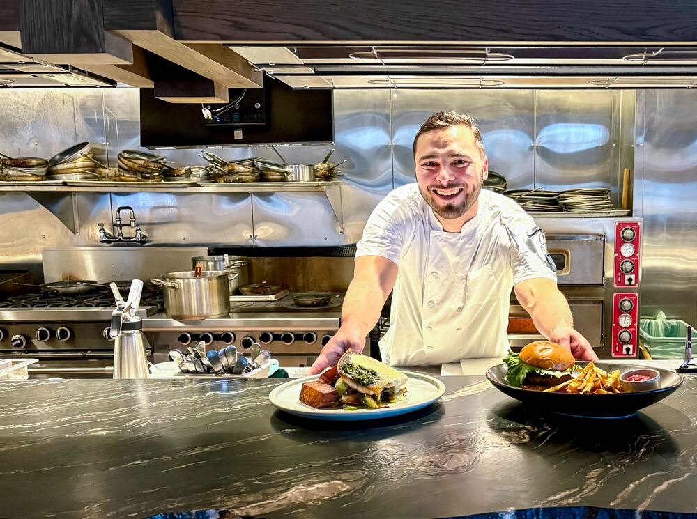 Head Chef of Good Folk Victor Bonilla slides two plates of food across a table in Banff.